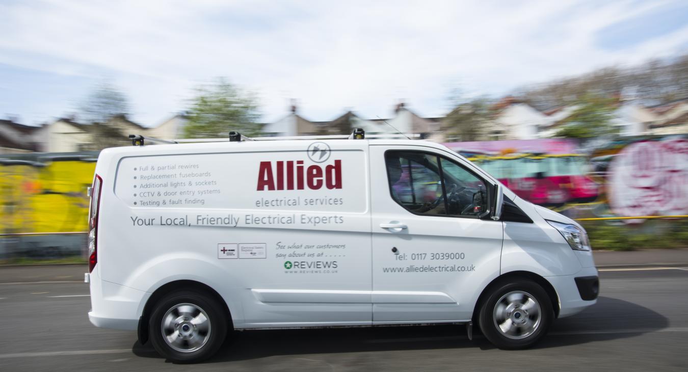 Allied Electrical van driving in front of a colourful wall. 